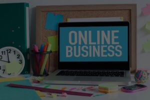 A cluttered desktop with an open laptop that reads "Online Business" in a white font and blue background.